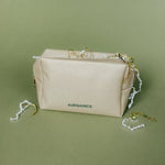 Gold cosmetic bag with AURGANICS branding on a green background by AURGANICS skincare for melanated glow-getters