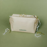 Gold cosmetic bag with AURGANICS branding on a green background by AURGANICS skincare for melanated glow-getters