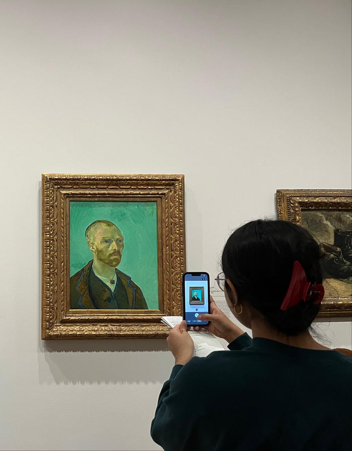Person taking a photo of a painting in an art gallery