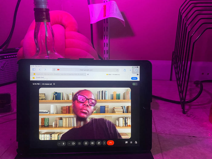 Person on a video call displayed on a tablet screen with a pinkish-purple hue.